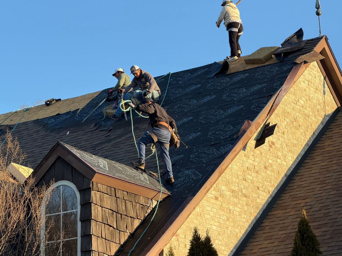 Three-man crew laying synthetic underlayment on a steep roof in Middle Tennessee