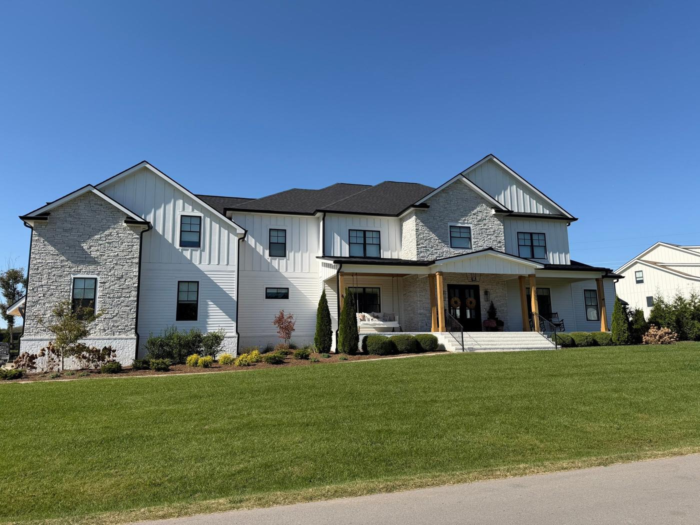 White modern farmhouse with a new black architectural shingle roof under a clear blue sky in Middle Tennessee