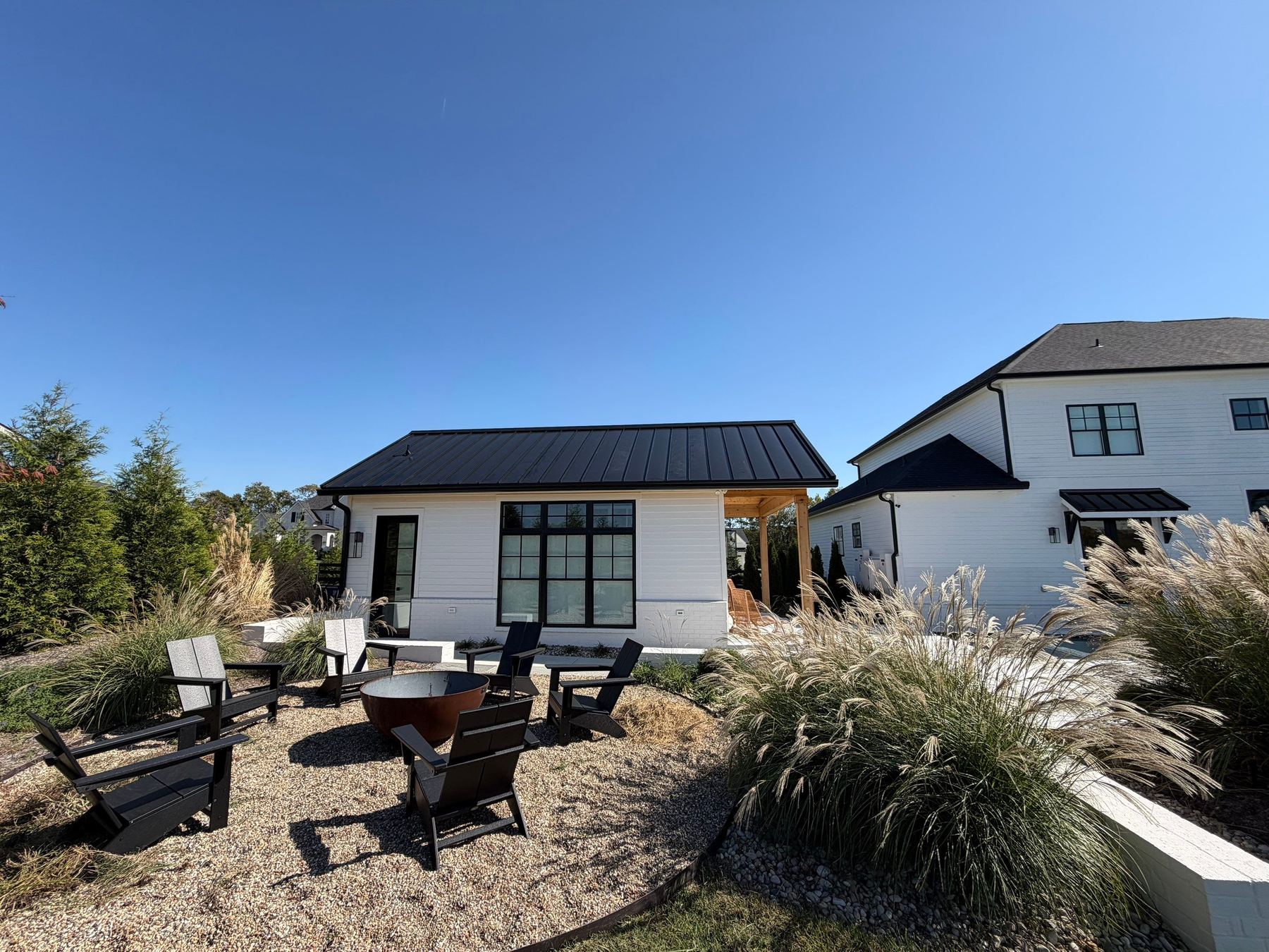 White cottage with a black standing-seam metal roof beside a gravel fire-pit patio in Middle Tennessee