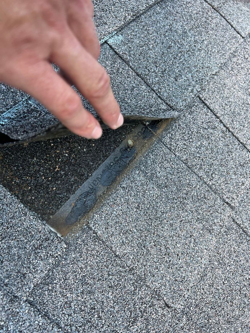 Inspector's hand lifting a cracked asphalt shingle during a roof inspection in Middle Tennessee