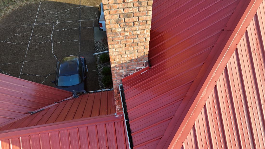 Red standing-rib metal roof with new chimney flashing, seen from above in Middle Tennessee